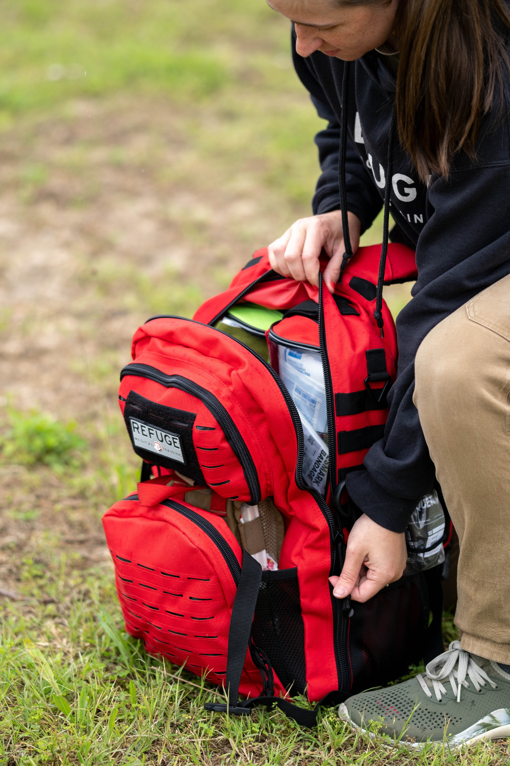 Refuge Medical Field Medic First Aid Backpack - Red, person opening backpack zipper