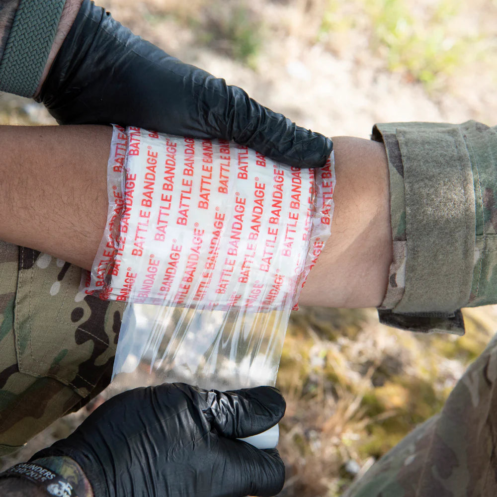 person applying battle bandage wrap to simulated wound on arm