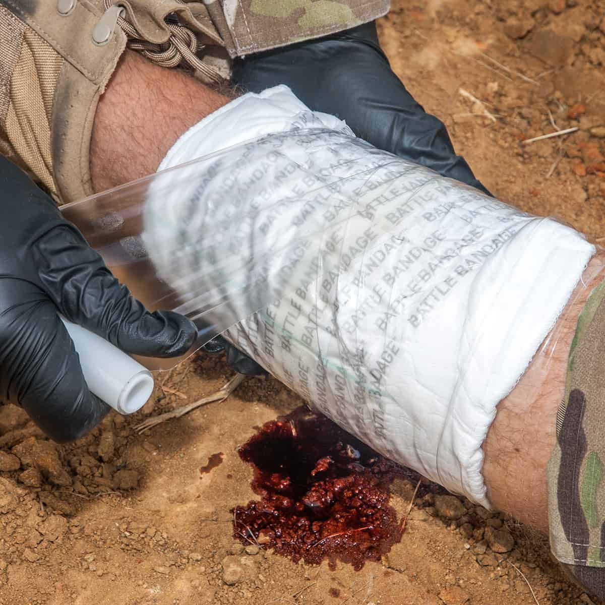 person applying battle bandage wrap to a simulated wound on leg