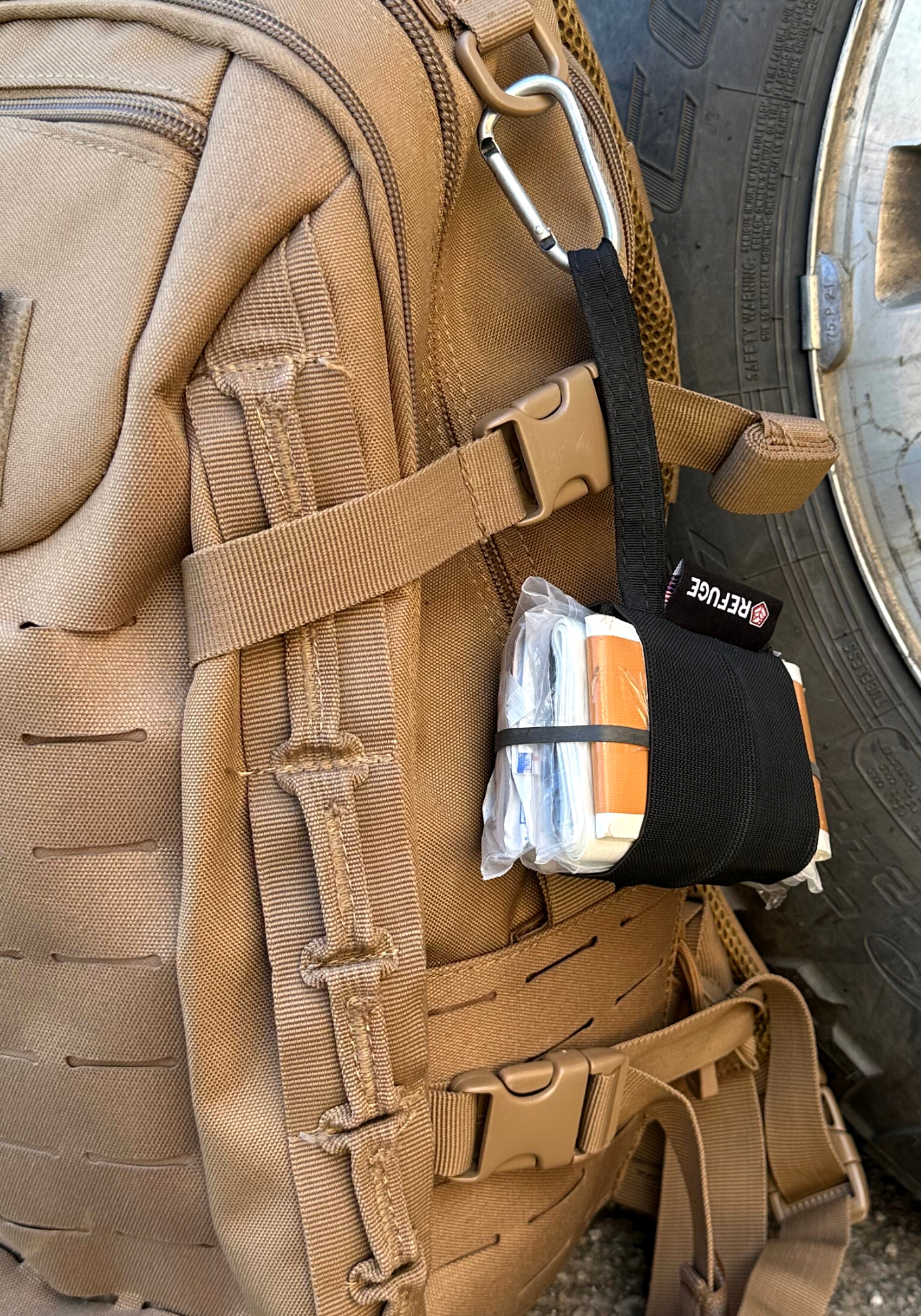 Black Boogie first aid kit hanging off a backpack from a carabiner 